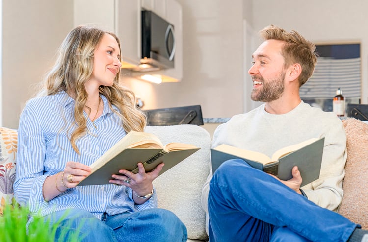 Happy couple sitting together reading on a couch